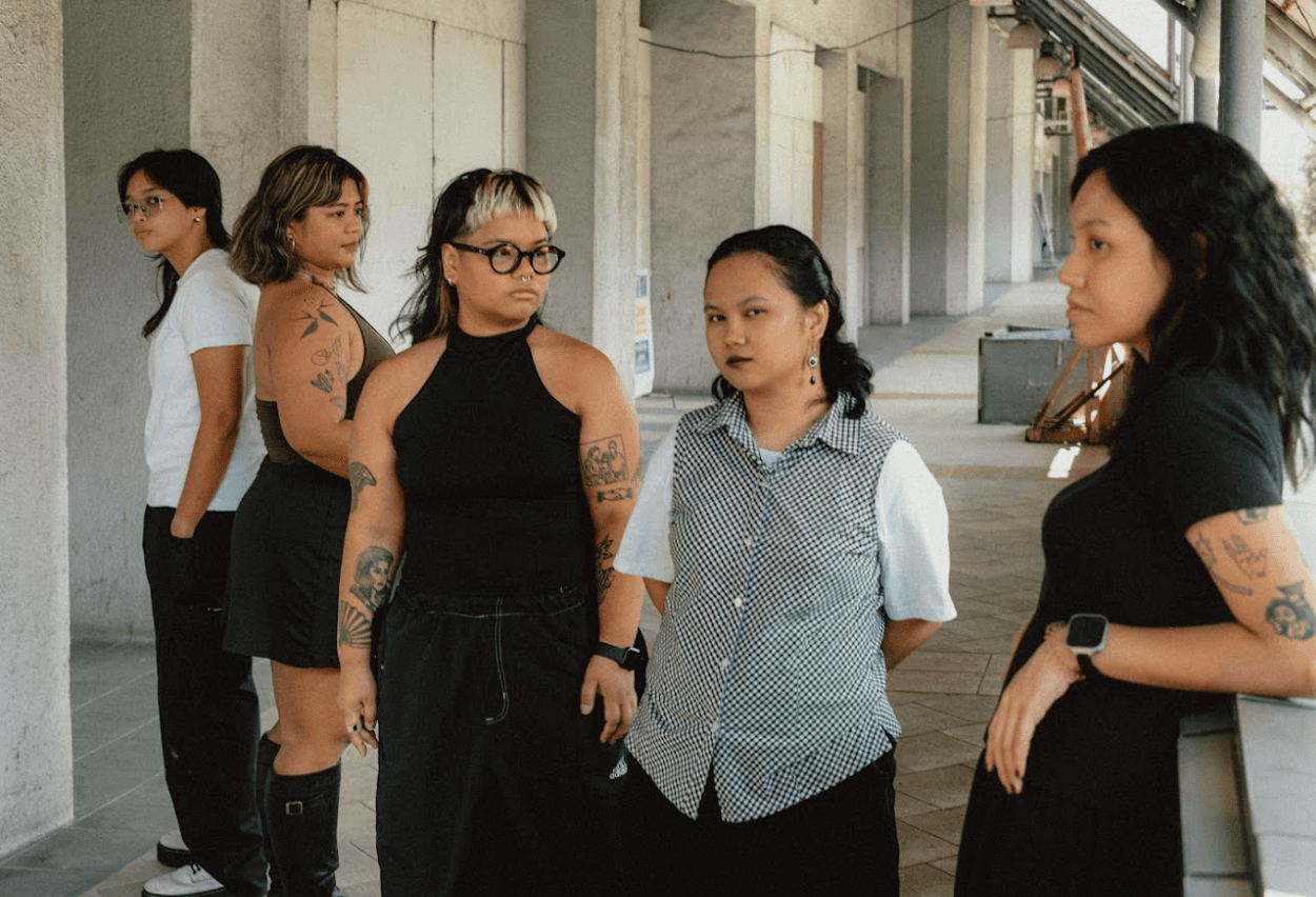 Five women lined up in a covered walkway, each looking off in a different direction.