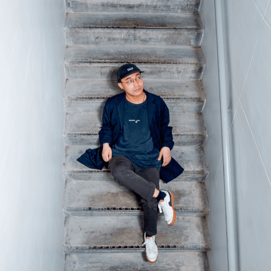 Man sitting on concrete stairs, legs crossed, shot from above.